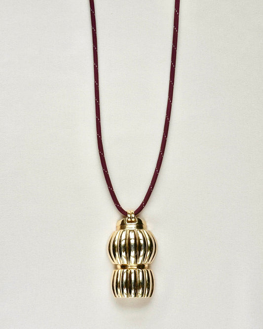 Full-length view of Standing O Abigail necklace featuring sculptural gold-tone brass pendant on burgundy paracord.