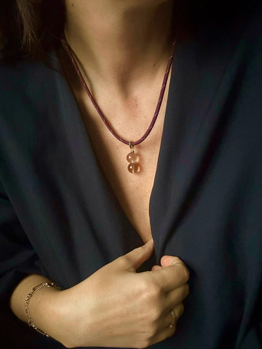 Burgundy paracord necklace with a pendant worn by a person against a dark background