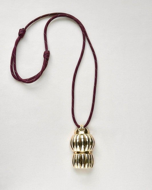 Vintage gold-tone brass pendant necklace on burgundy paracord, handmade by Standing O. Flatlay view showing adjustable knotted cord