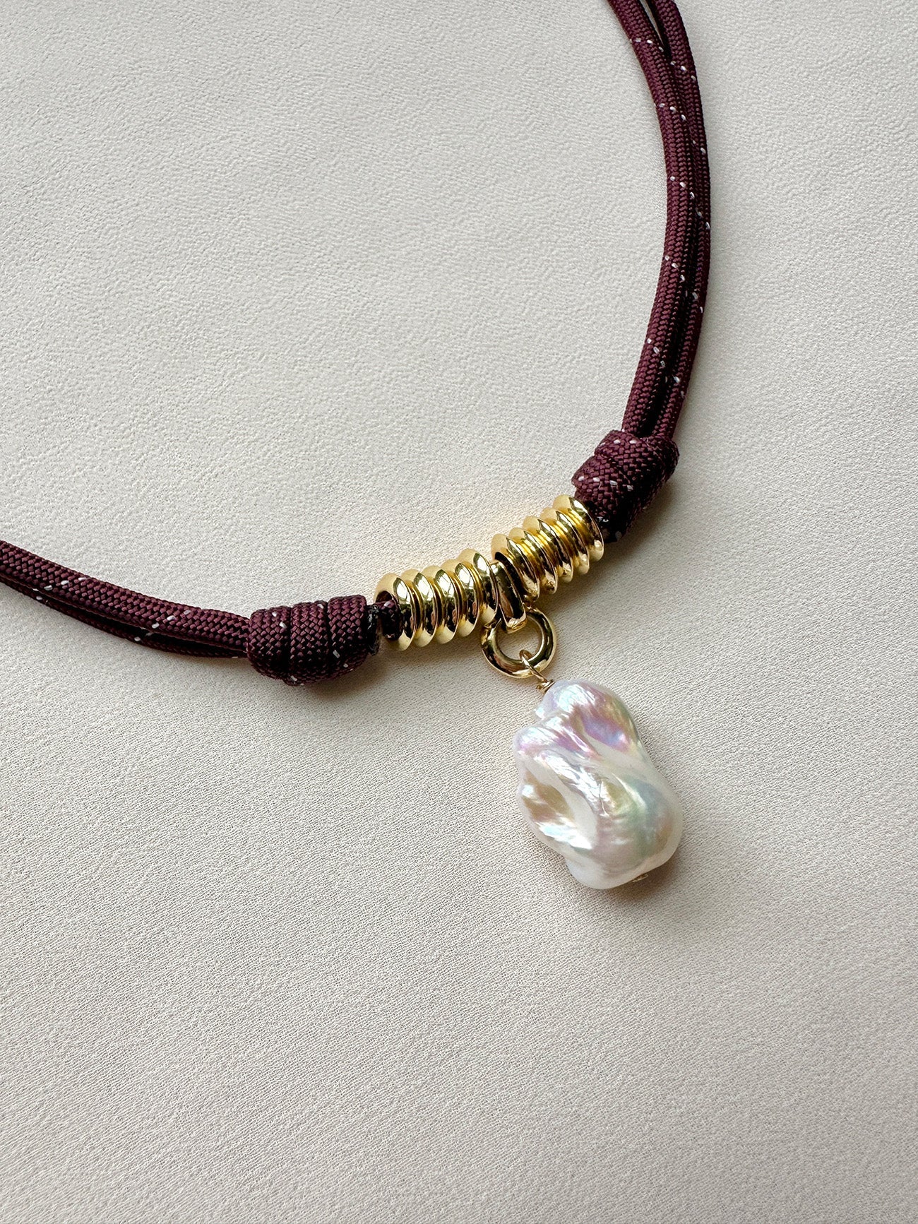 Close-up of a burgundy paracord and pearl necklace