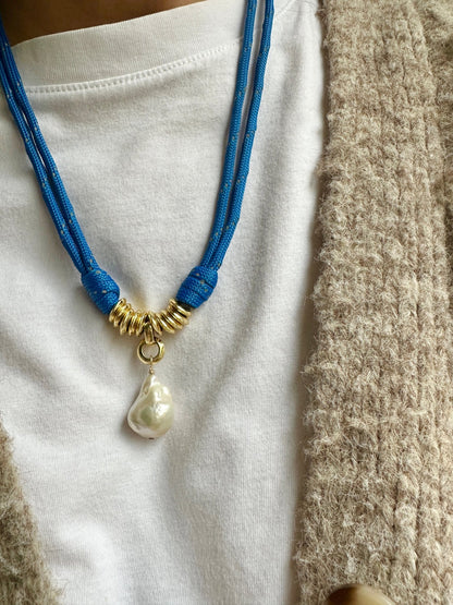 Blue cord necklace with a big baroque pearl pendant on a white shirt