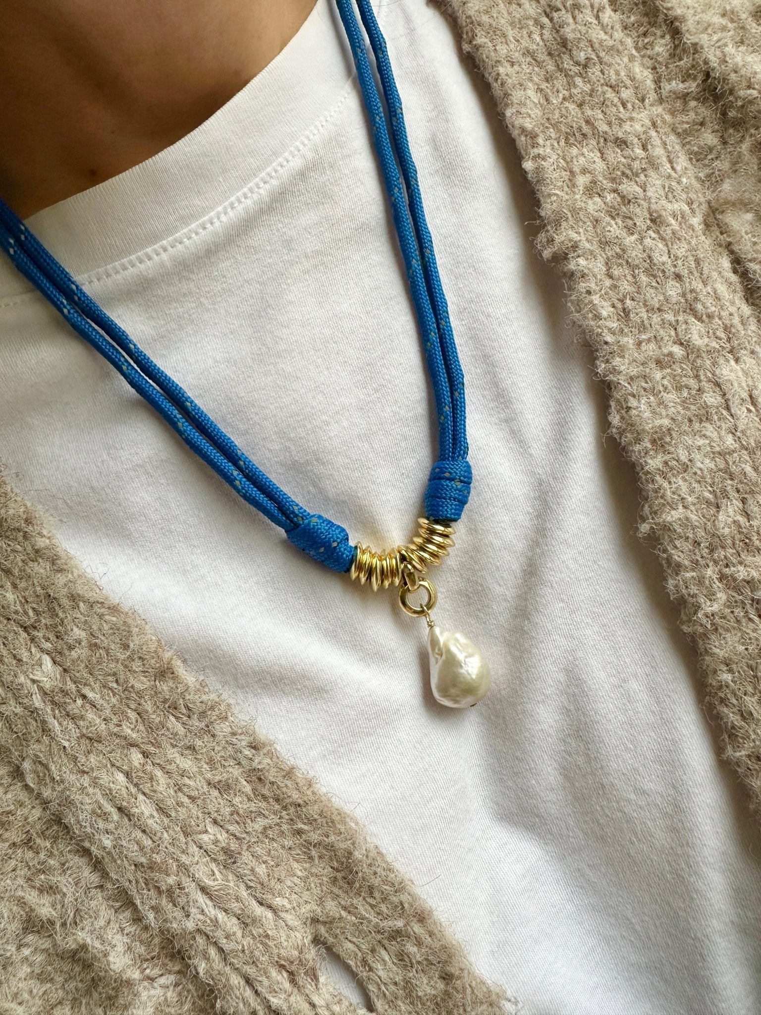 Blue paracord necklace with a pearl pendant on a white shirt