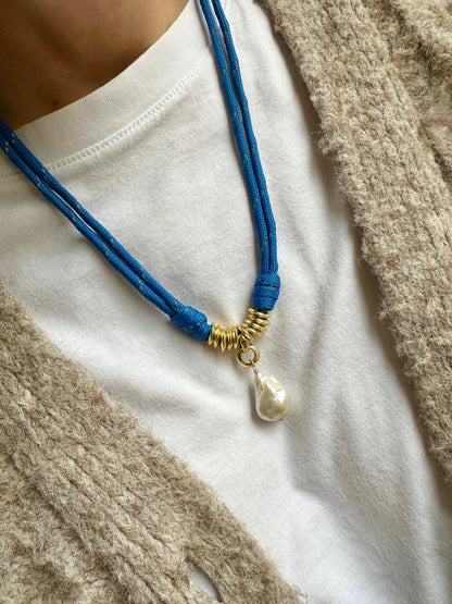Blue paracord necklace with a pearl pendant on a white shirt