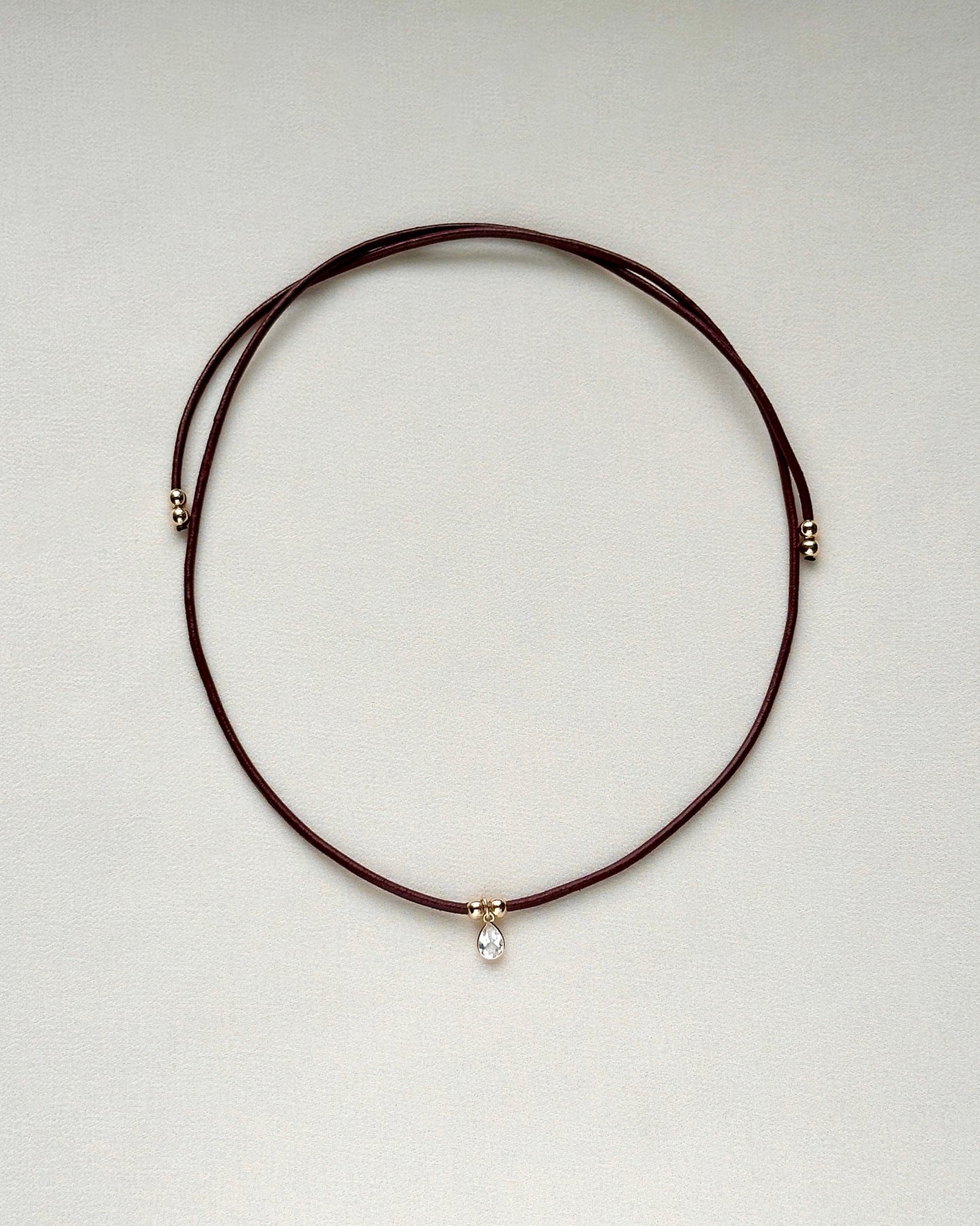 full view of burgundy leather cord necklace with white topaz and gold-filled accents