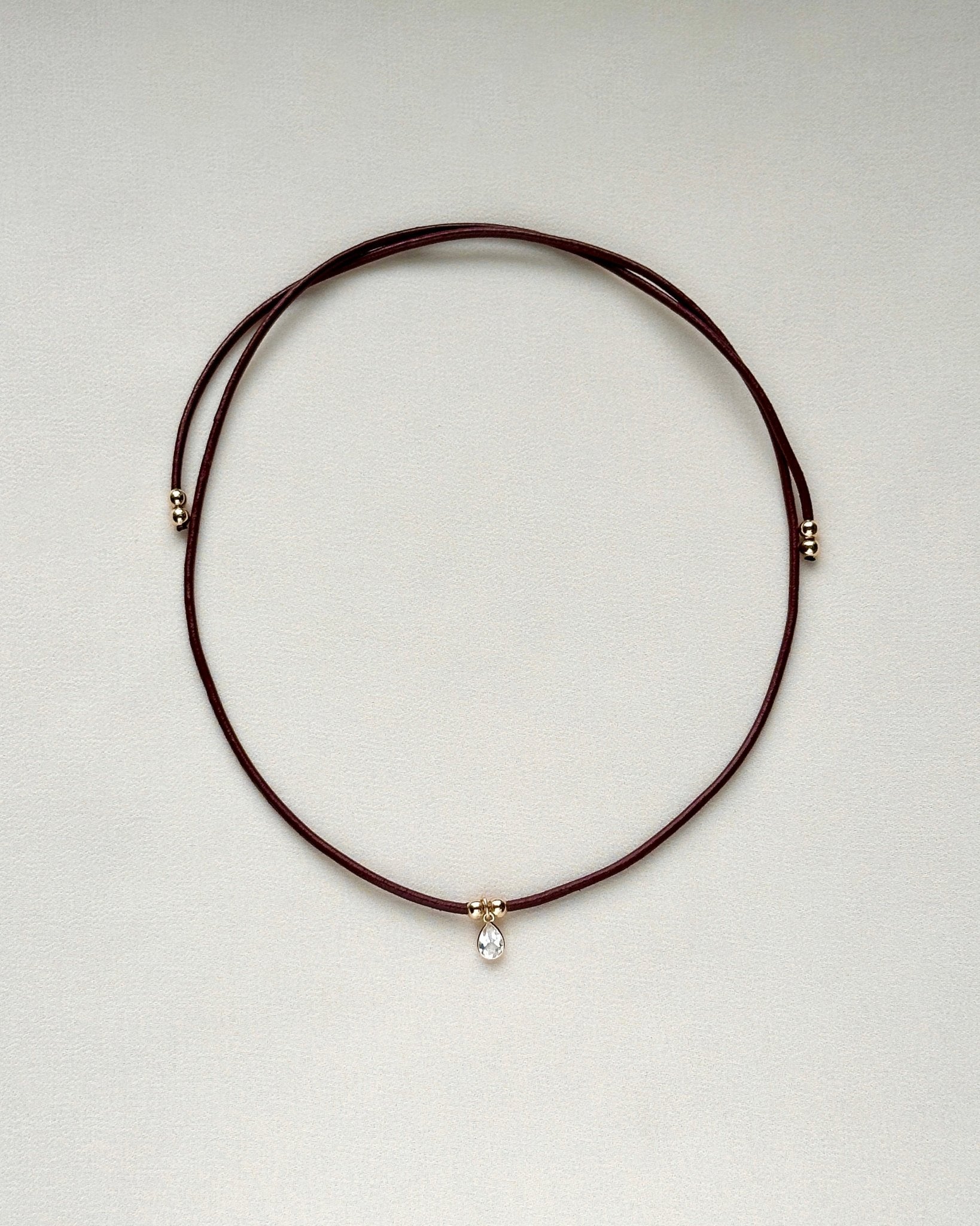 full view of burgundy leather cord necklace with white topaz and gold-filled accents