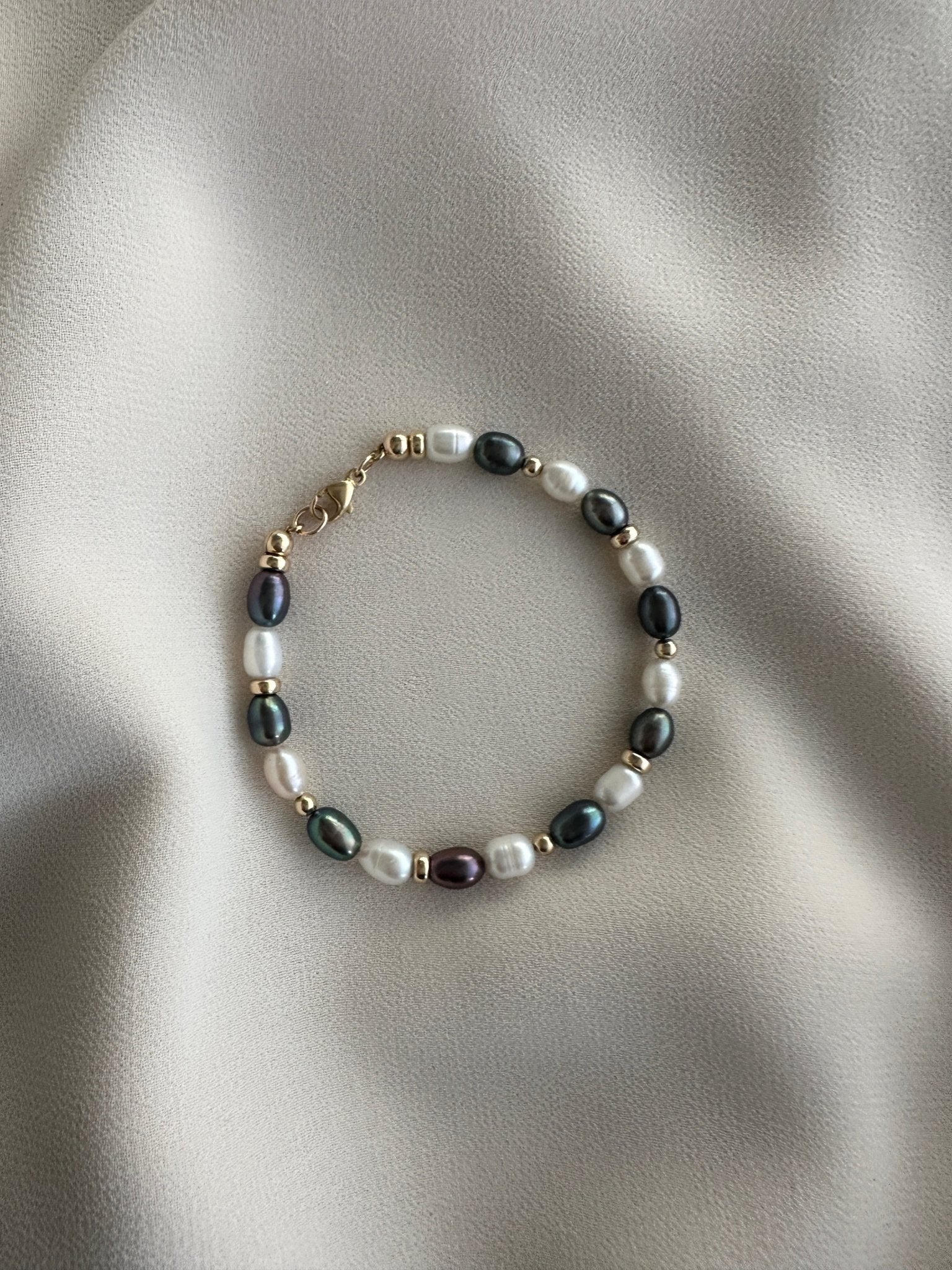 Pearl bracelet with gold accents on a beige fabric background