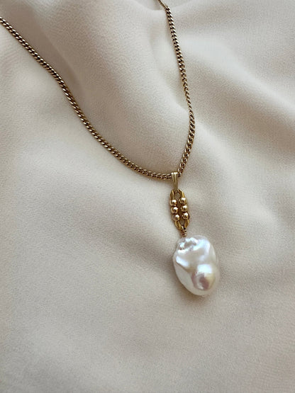 Pearl necklace with a gold chain on a beige fabric background