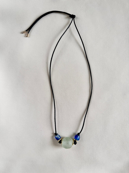 Necklace with a green and blue glass beads on black leather cord on a white background