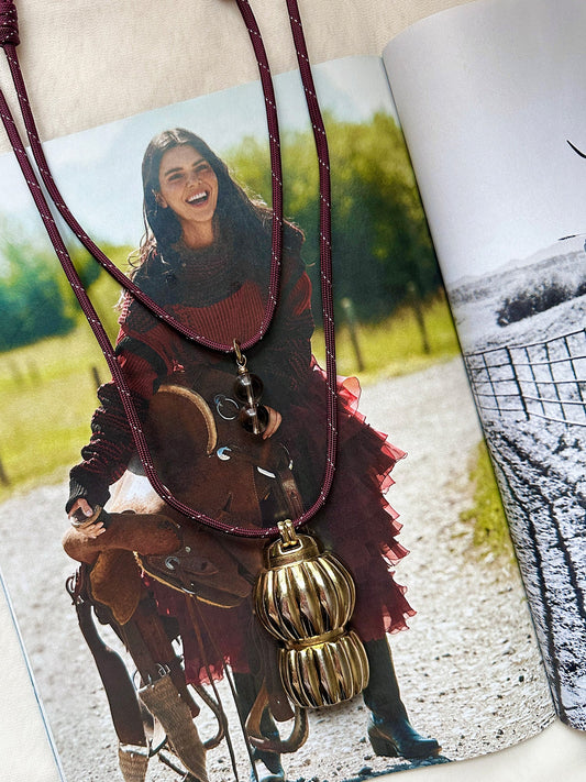 Paracord necklaces with gold pendants on a magazine page