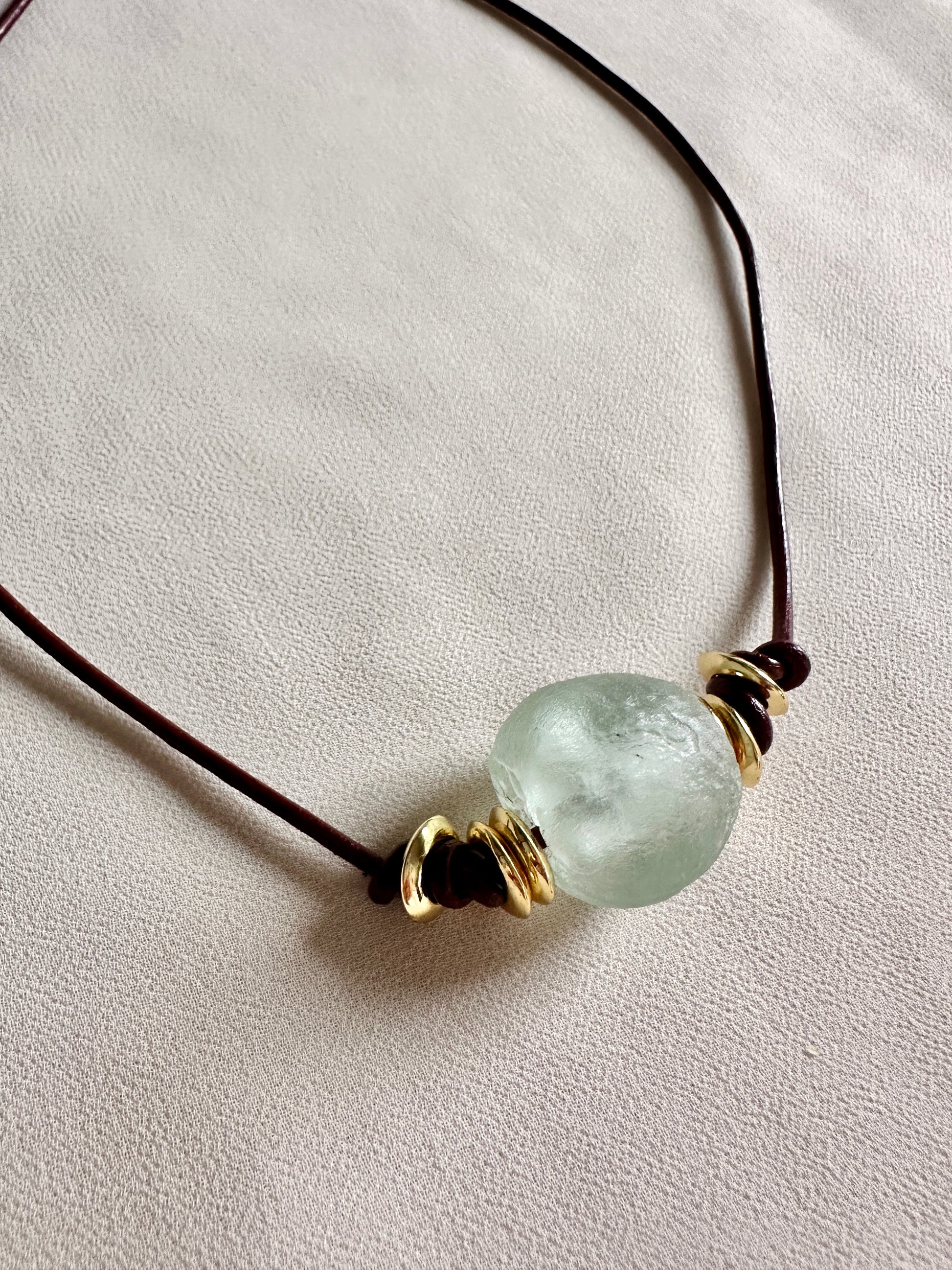 Necklace with a green glass pendant on a leather cord and white background