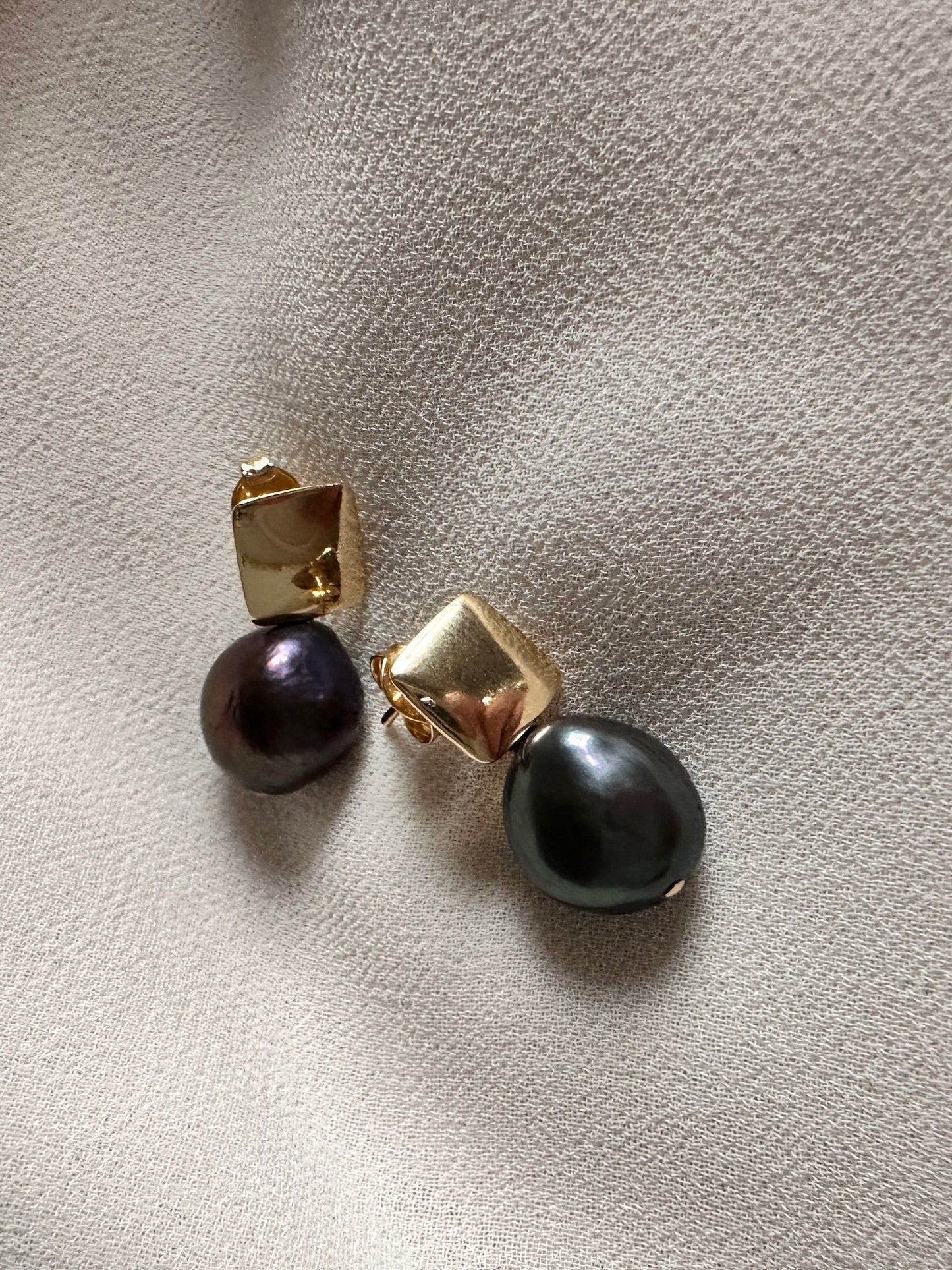 Close up of dark freshwater pearl and gold square stud